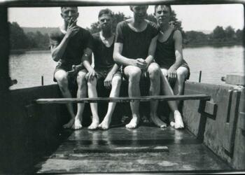 Ralph and three male friends in swimsuits on a small boat.