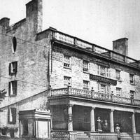 A black and white image of the Frontier House in Lewiston. The building is three stories tall with a large front porch and tall chimneys at both ends of the building.