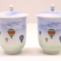 two porcelain containers decorated with paintings of hot air balloons