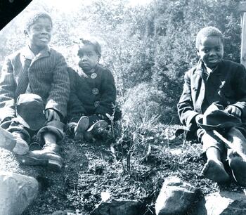 Photograph of three children sitting on a hill