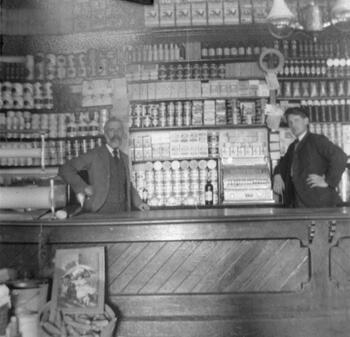 Photograph of two men behind a counter in a store.