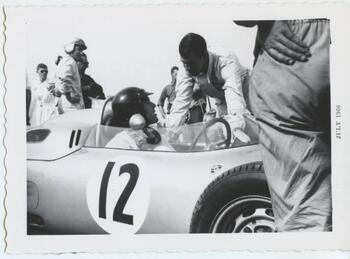 two men talking while one is in a racecar