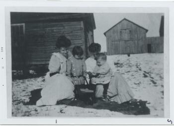 Two mothers and their young children, sitting outside
