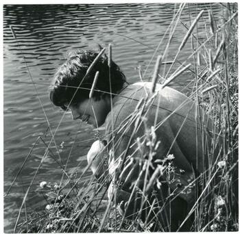 a boy near a lake with plants
