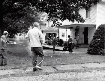 men with a rowboat in a flooded backyard