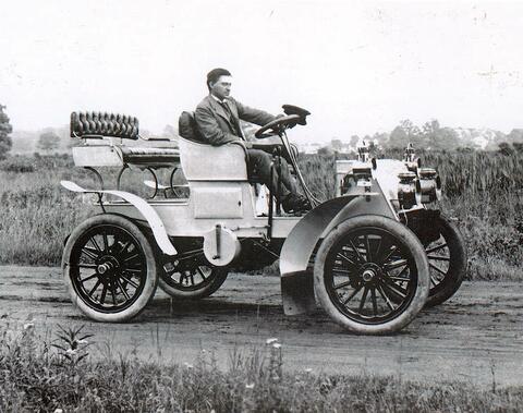 Man riding 1920s era automobile
